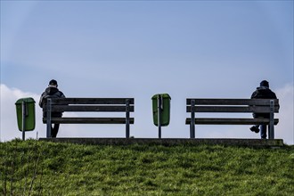 Benches on a dyke on the Weser in Bremerhaven, two people sitting symmetrically away from each