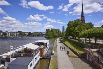 Main river with riverside promenade and Evangelische Dreikönigskirche under blue sky with cumulus