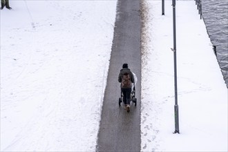 Winter in the city, cleared riverside path on the Main, woman with pram, Frankfurt, Hesse, Germany,