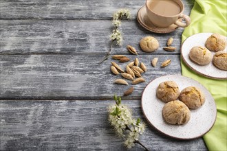 Almond cookies and a cup of coffee on a gray wooden background and green linen textile. Side view,