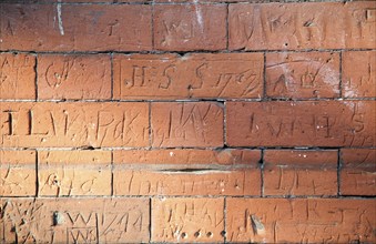 Eighteenth century children's graffiti scratched into red brick of former school building, Dedham,