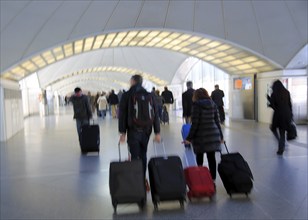 Blurred motion image of passengers pulling luggage bags along a bright corridor, Atocha railway