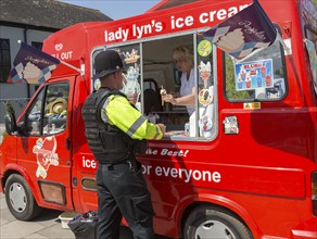 Policeman getting an ice-cream cone from an ice cream van, Salisbury, Wiltshire, England, UK