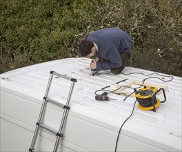 Cutting through roof of white metal camper van conversion to install ventilation window, UK