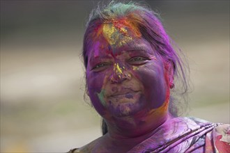 Woman covered in colourful dye celebrating the Holi festival, Festival of Colours in Mathura, Uttar