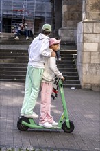 Two young men ride together on a Bolt rental e-scooter, Essen, North Rhine-Westphalia, Germany,