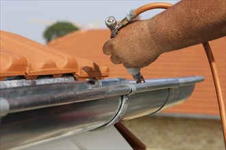 Roofer doing tinsmith work on a gutter