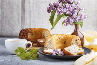 Cakes with raisins and chocolate and a cup of coffee. lilac flowers on a gray concrete background,