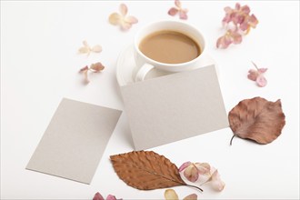 Composition with gray paper business card, brown beech autumn leaves, hydrangea flowers and cup of