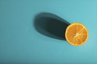 Ripe cut orange on blue pastel background. Top view, flat lay, copy space, hard light. Tropical,