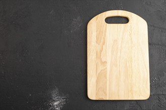 Empty rectangular wooden cutting board on black concrete background. Top view, copy space, flat lay