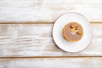 Sweet tartlets with almonds and caramel cream on a white wooden background. top view, flat lay,