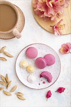 Purple macarons or macaroons cakes with cup of coffee on a white concrete background decorated with