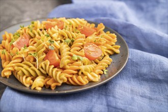 Tortiglioni semolina pasta with tomato and microgreen sprouts on a black concrete background and