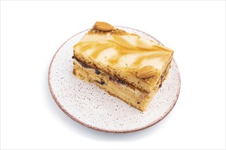 Honey cake with milk cream, caramel, almonds isolated on a white background. Side view, close up