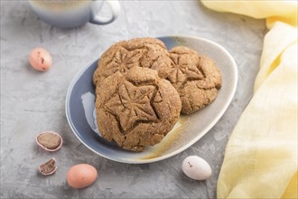 Homemade oatmeal cookies with a cup of cocoa and a yellow textile on a gray concrete background.