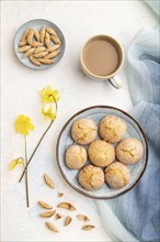 Almond cookies and a cup of coffee on a white concrete background and blue linen textile. Top view,