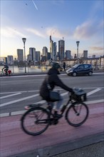 Skyline of the city centre of Frankfurt am Main, cyclist on the Ignatz-Bubis-Bridge, dusk, river