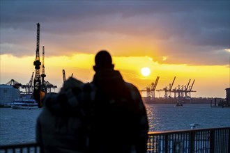 Port of Hamburg, couple looking at the Blohm + Voss shipyard, evening, cranes of the container