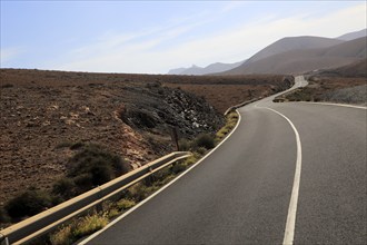 Tarmac road crossing barren desert mountainous land between Pajara and La Pared, Fuerteventura,