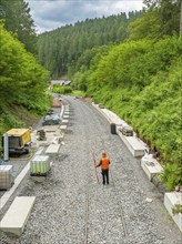 Workers on a construction site carrying out track work in a green, wooded environment, Gleisbau