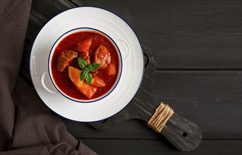 Stew with potatoes, in tomato sauce, with spices and herbs, close-up, no people, on a black