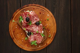 Sandwich, grain bread, with cream cheese and salami, black olives, micro-greens, top view,