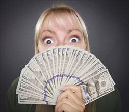 Girl holding thousands of dollars in one hundred dollar bills fanned out in her hand