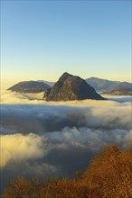 Mountain Peak San Salvatore Above Cloudscape with a Autumn Tree and Sunlight with Clear Sky in