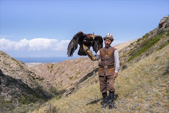 Traditional Kyrgyz eagle hunter with eagle in the mountains, near Kysyl-Suu, Kyrgyzstan, Asia