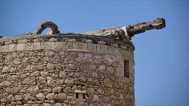 A historic round tower with stone walls and old wooden beams under a clear sky, windmill, ruin,