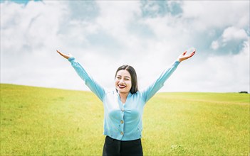 Portrait of beautiful girl spreading arms enjoying the countryside. Happy young woman spreading