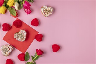 Valentine's Day composition with roses, hearts and envelope, heart-shaped cupcakes, on a pink