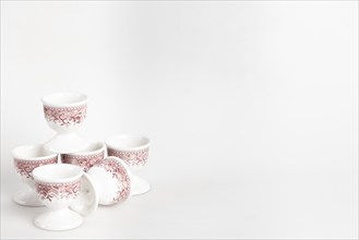 Ceramic egg cup with reddish pattern on white background, copy room