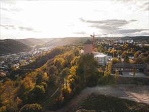 Autumnal cityscape with an old tower and construction cranes at sunset, Horb, Black Forest,