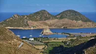 Panorama of a bay with boats and surrounded by hills under a blue sky, Petras Beach, Kalikatsou