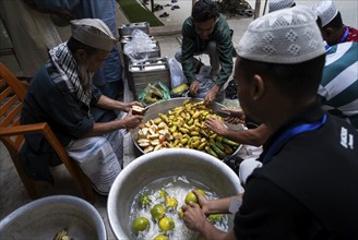 Muslim people cuts fruits to distribute during 'iftar' meal, to break their fast during the holy