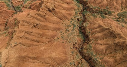 Eroded mountain landscape, top-down, canyon with red and orange rock formations, aerial view,