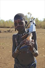 South Ethiopia, in Maco National Park, Mursi tribe, Mursi boy with painted face and rifle,