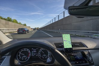 Driving on the A73 motorway with navigation by mobile phone, noise barriers on the left and right,