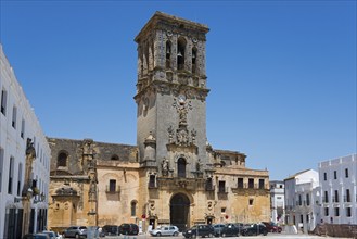 A town square with an impressive bell tower and surrounding buildings in bright weather, Basilica