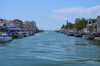 Coastal town with colourful houses, boats in the water and a lighthouse in the background on a