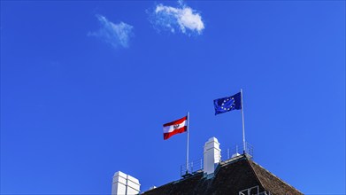 The Austrian national flag and the flag of the European Union fly over the Federal Chancellery,