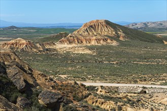 Vast landscape with rocky hills and a road under a clear blue sky, Bardenas Reales Natural Park,