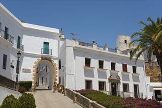 Architectural view with white buildings and a stone archway under sunshine, Arco de la Villa, Plaza