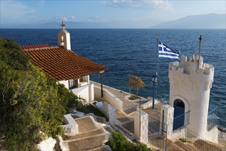 Small chapel on the coast with a view of the sea and a Greek flag, Church of Agios Nikolaos