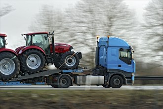 Truck, lorry, articulated lorry with new tractors driving fast on the A92 motorway, motion blur,