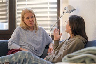 Mother and daughter, teenage, 13 years old, in a confidential conversation, at home