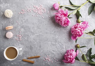 Pink peony flowers and a cup of coffee on a gray concrete background. Morninig, spring, fashion