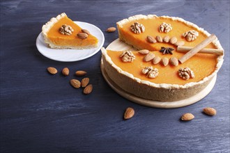 Traditional american sweet pumpkin pie decorated with nuts, on dark blue wooden background. close